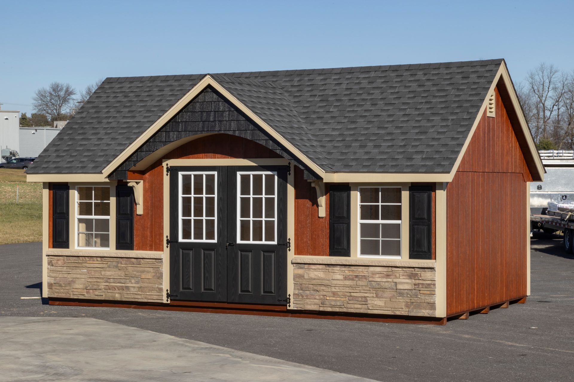 a small wooden house with a black roof and shutters