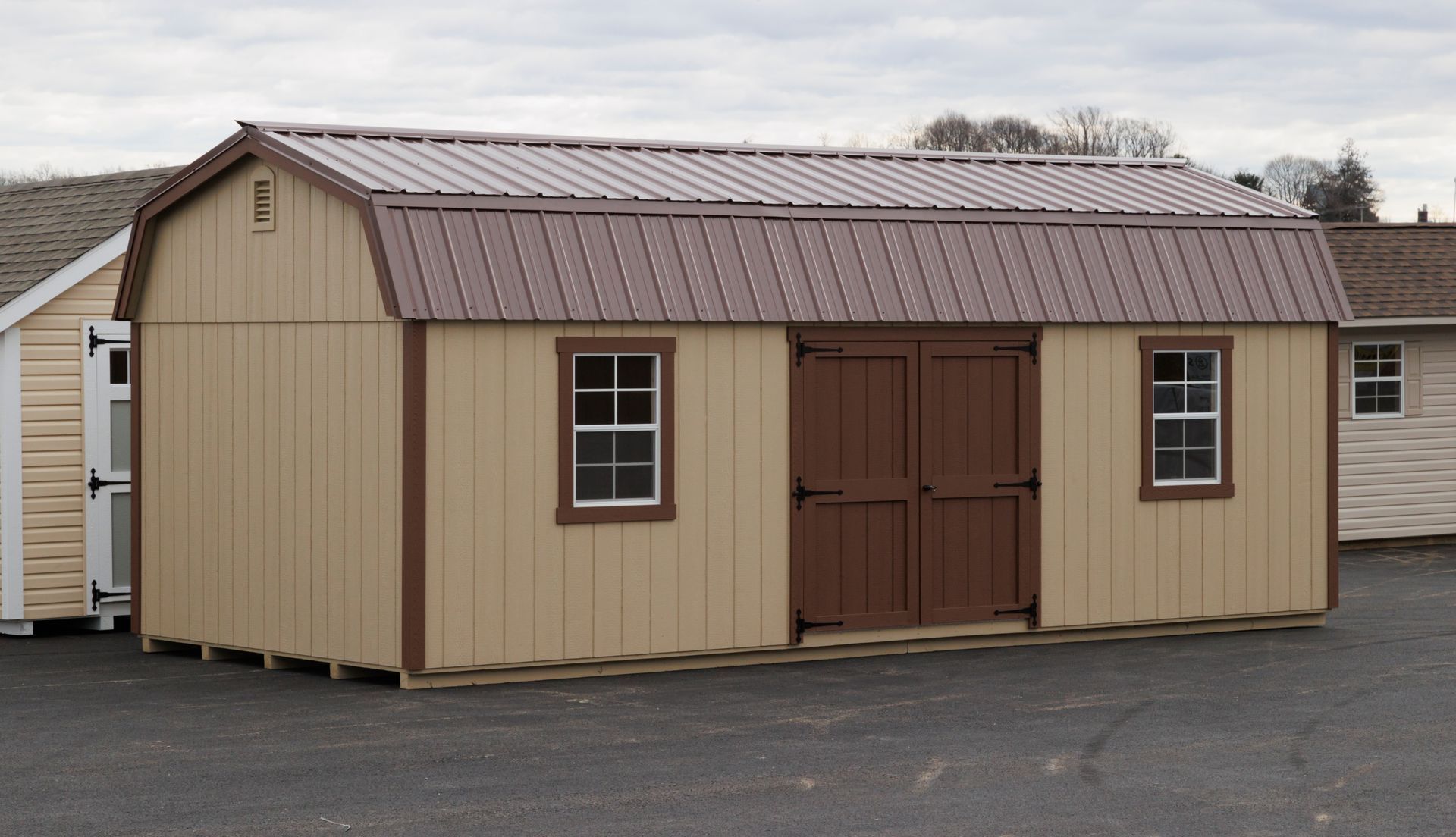 a tan shed with a brown door and windows