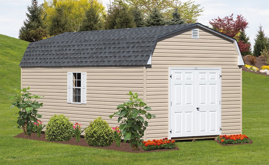 a shed with a black roof is sitting in the middle of a grassy field .