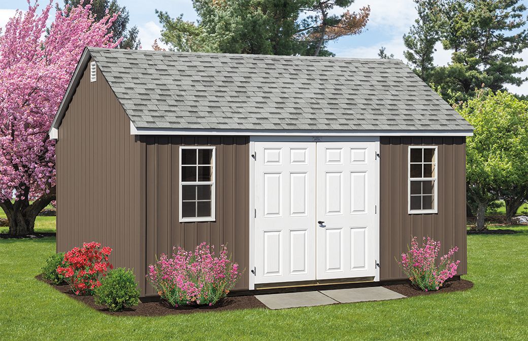 a brown shed with white doors and windows is sitting on top of a lush green lawn .