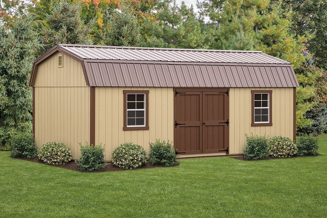 a shed with a brown door and windows is sitting in the middle of a lush green field .