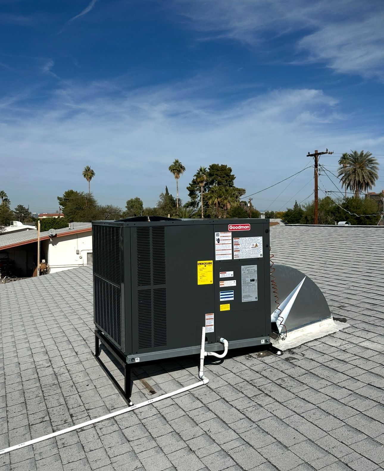 Dark gray HVAC unit on a rooftop with clear blue sky in background.