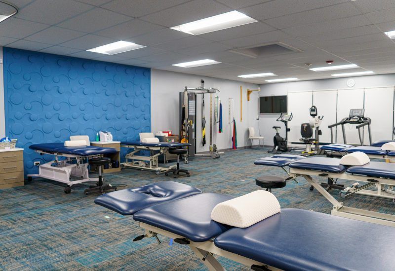 A physical therapy room with blue tables and a blue wall
