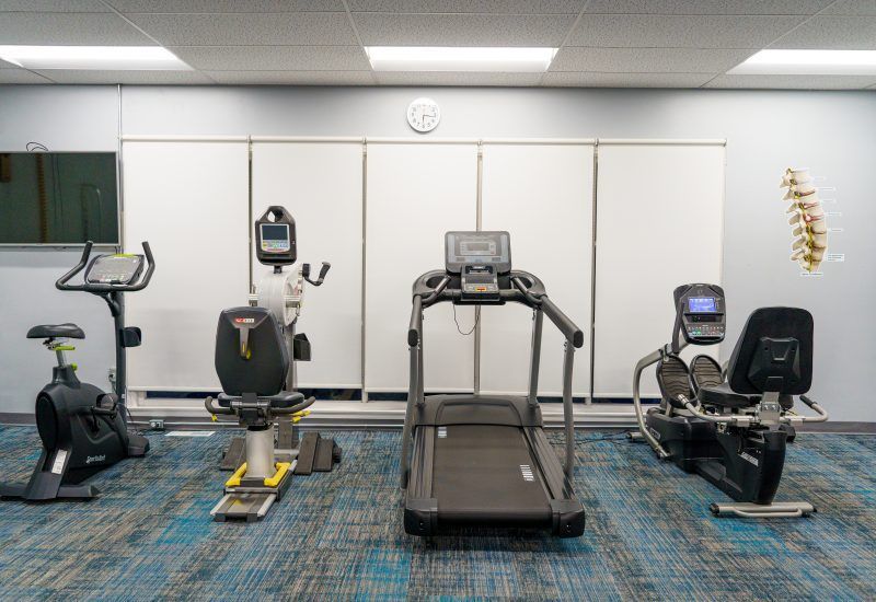 A gym with a treadmill, exercise bike, and recumbent bike