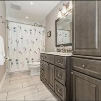 Bathroom with white tile, a gray vanity, and a floral shower curtain.