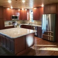 Kitchen with wooden cabinets, stainless steel refrigerator, and granite countertops.