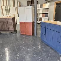 Interior with various cabinets in different colors, including blue, brown, and white, on a concrete floor.