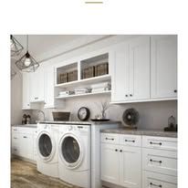 White laundry room with washer, dryer, cabinets, and decor.