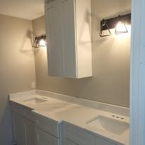 Bathroom with white cabinets, countertops, and two sconces.