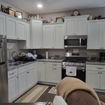 Kitchen with white cabinets, appliances, and a partially visible armchair.