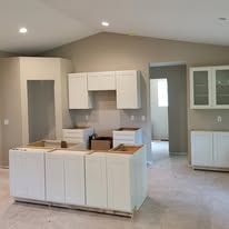 Empty kitchen with white cabinetry and an island.