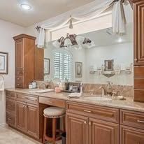 Bathroom vanity with a mirror, wooden cabinets, a stool, and a window.