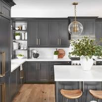 Kitchen with dark gray cabinets, white countertops, wooden floors, and a hanging light.