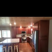 Kitchen with wood ceiling, cabinets, appliances, and a central island with a counter.