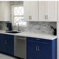Kitchen with white and blue cabinets, stainless steel appliances, and a tiled backsplash.