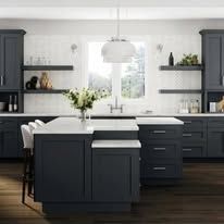 A modern kitchen with a dark blue island and cabinets, white countertops and backsplash, and a large window.