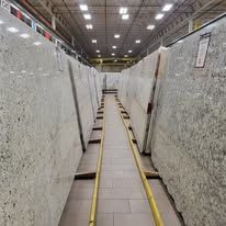 Rows of large granite slabs stored in a warehouse with a central walkway.