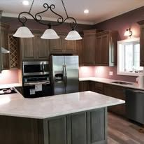 Kitchen with island, dark cabinets, granite counters, stainless appliances, pendant lights.