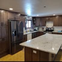 Kitchen with dark wood cabinets, stainless steel refrigerator, and light countertops.