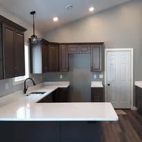 Kitchen with dark cabinets, white countertops, and a pendant light. A door is in the background.