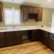 Kitchen with dark cabinets, a window, and light-colored countertops and flooring.