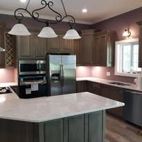 Kitchen with cabinets, island, and stainless steel appliances. A chandelier hangs above the island.