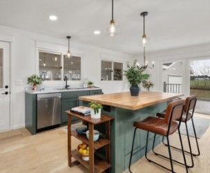 Kitchen with blue-green cabinets, wood island, and brown leather bar stools.