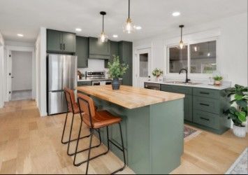 Green kitchen with wood island, stainless steel appliances, and leather bar stools.