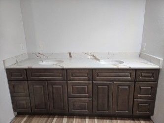 Bathroom vanity with two sinks, gray cabinets, and marble countertop.