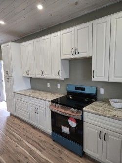 White kitchen cabinets with black stove and granite countertops.