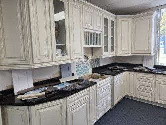 White kitchen cabinets with black countertops. Samples and decor on the counters.