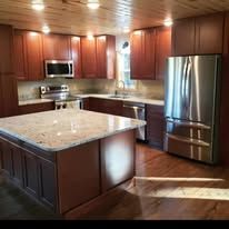 Kitchen with wooden cabinets, stainless steel refrigerator, and granite countertops.