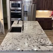 Kitchen with granite countertop, stainless steel appliances, and dark cabinets.