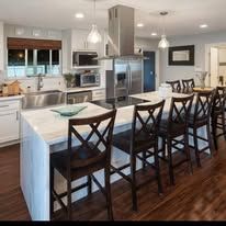 Modern kitchen with island, bar stools, and stainless steel appliances.