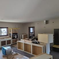Unfinished kitchen with cabinets and appliances in a room with white walls, and bright natural light.