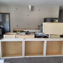 Unfinished kitchen cabinets in a room, with various cabinet boxes, some on the floor.