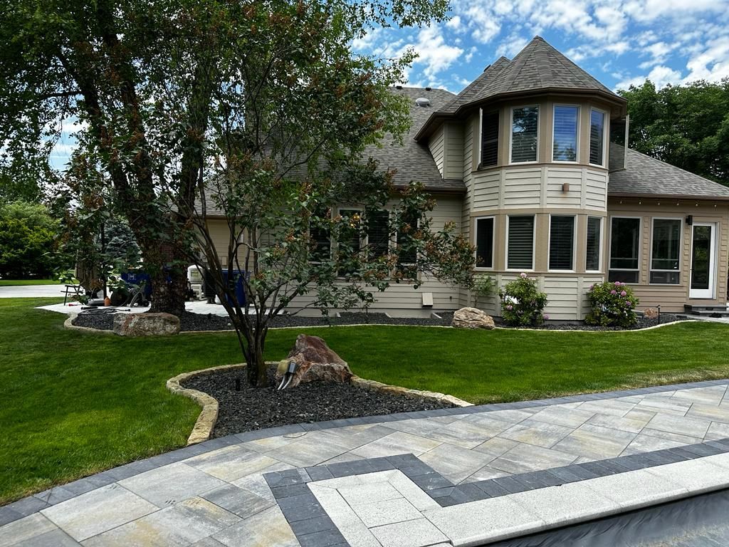 Suburban house with wraparound porch, large bay window, and manicured lawn beside a stone walkway