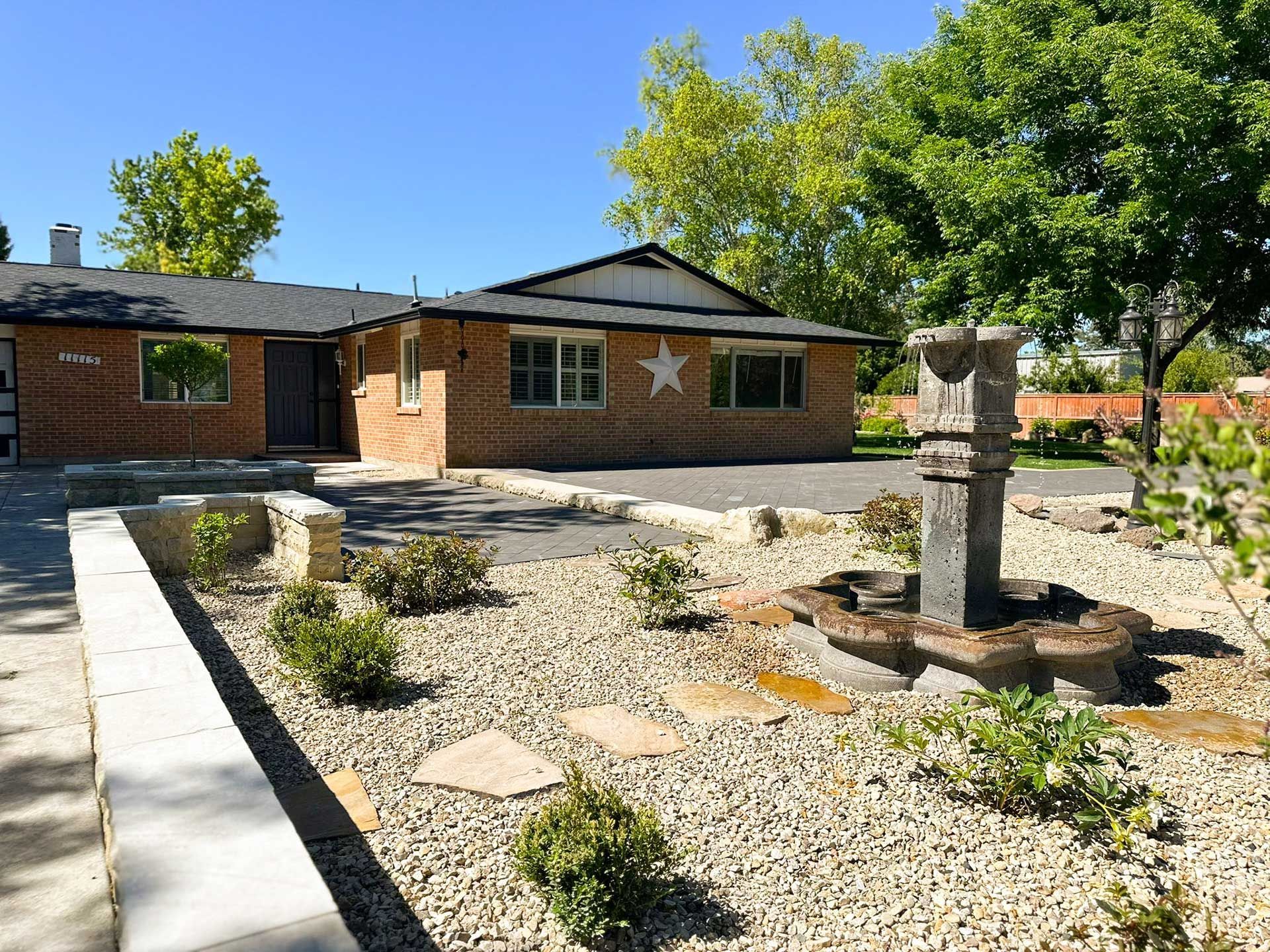 Brick house with star decorations and a gravel courtyard featuring a small stone fountain.