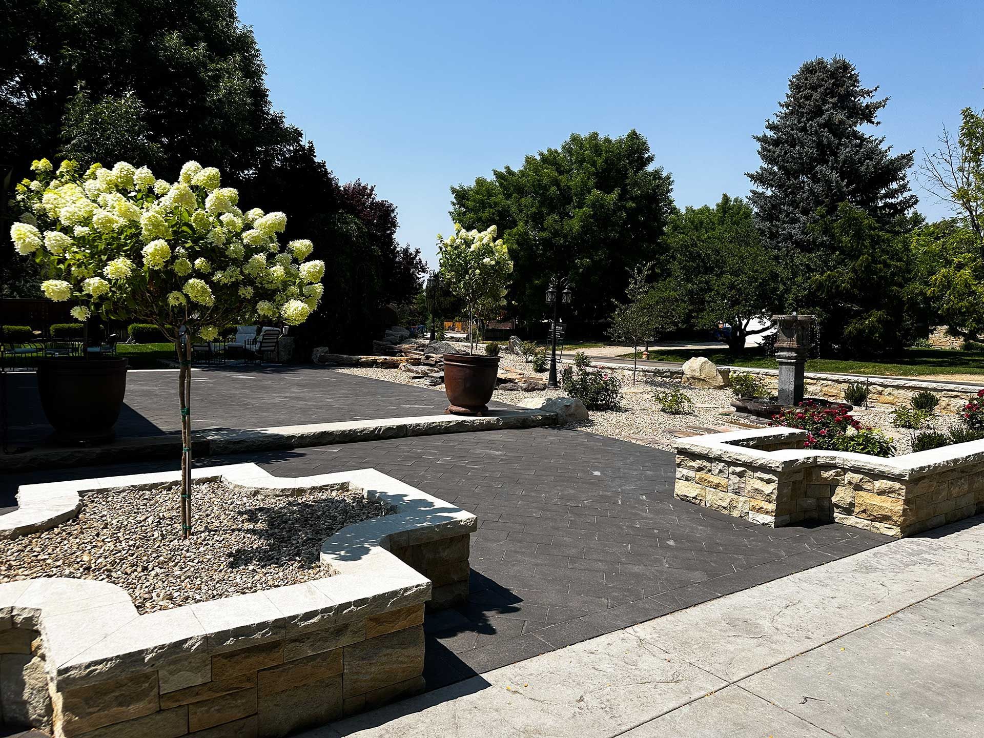 Sunny landscaped garden with stone benches, gravel paths, and white hydrangea bushes