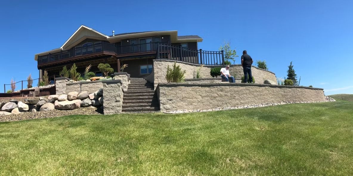 Stone house with a porch on a grassy hill under a blue sky