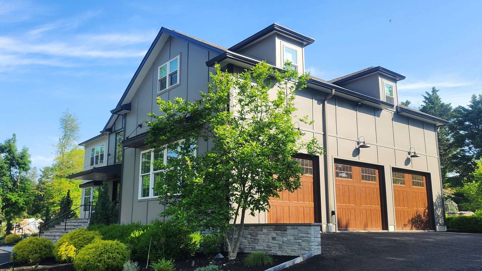 Stone and stucco house with multiple gables, arched entry, and dark shutters.