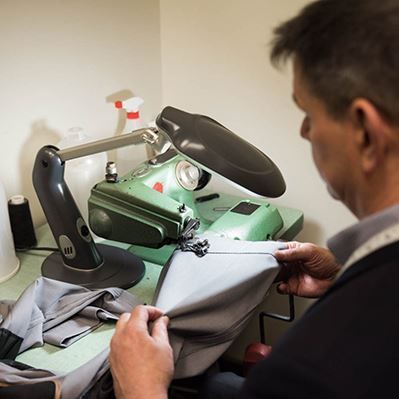 A man is working on a sewing machine with a magnifying glass.