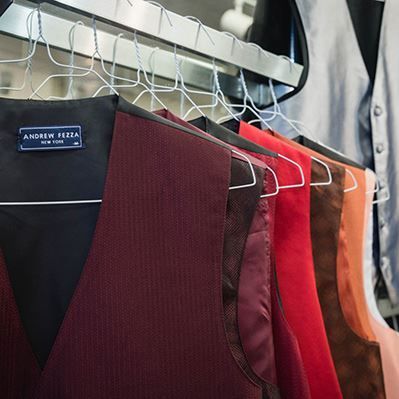 A row of vests are hanging on a rack in a store.