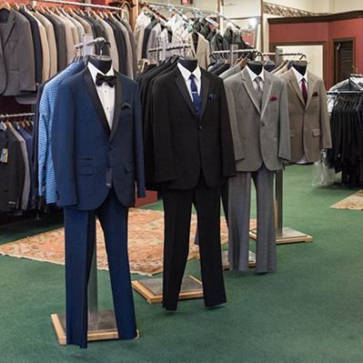 Men 's suits are displayed on mannequins in a store