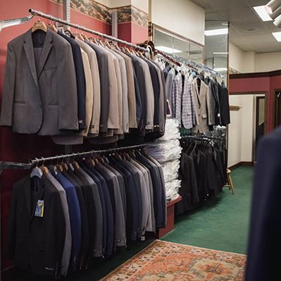 A row of suits hanging on racks in a store.