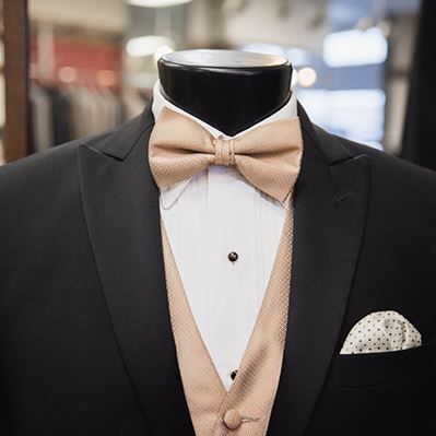 A mannequin is wearing a tuxedo with a bow tie and vest.