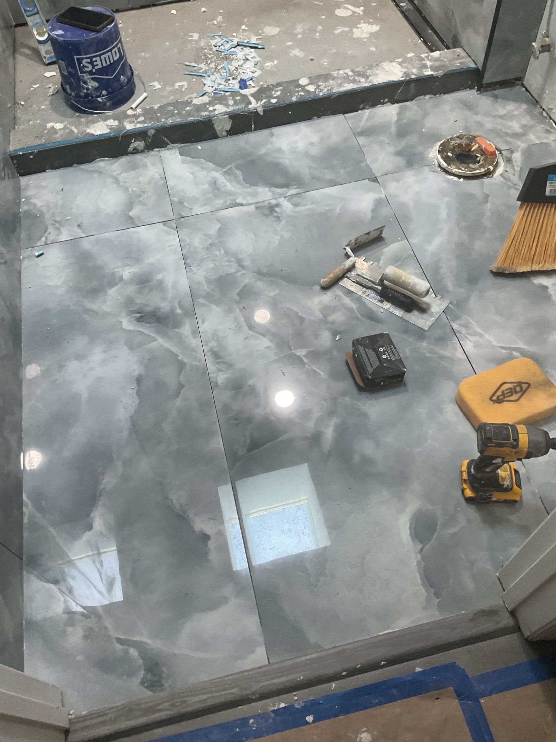 Worker’s tools scattered on a gray tiled floor in a room under construction.