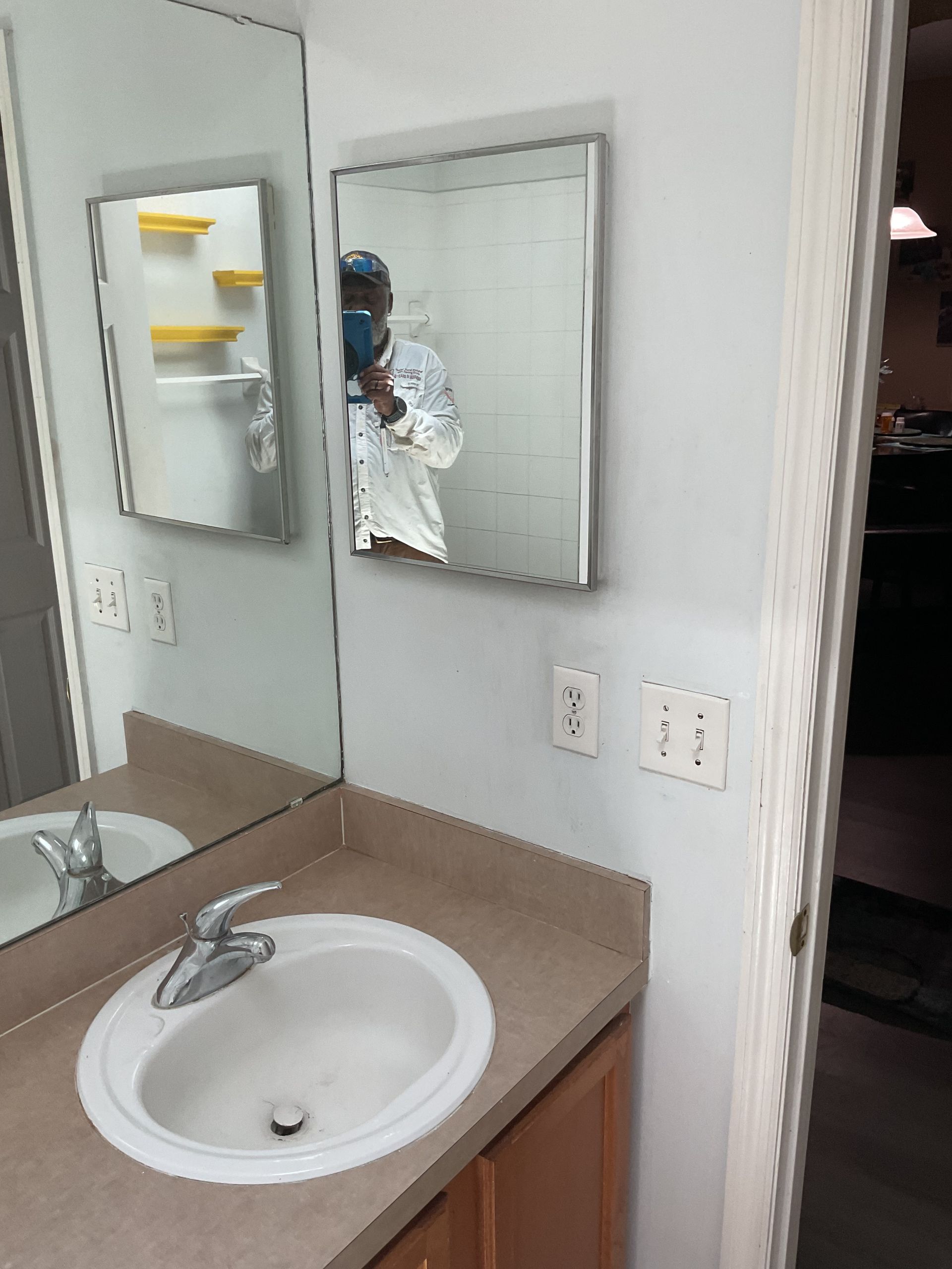 Bathroom sink and mirror with a person reflected taking the photo.