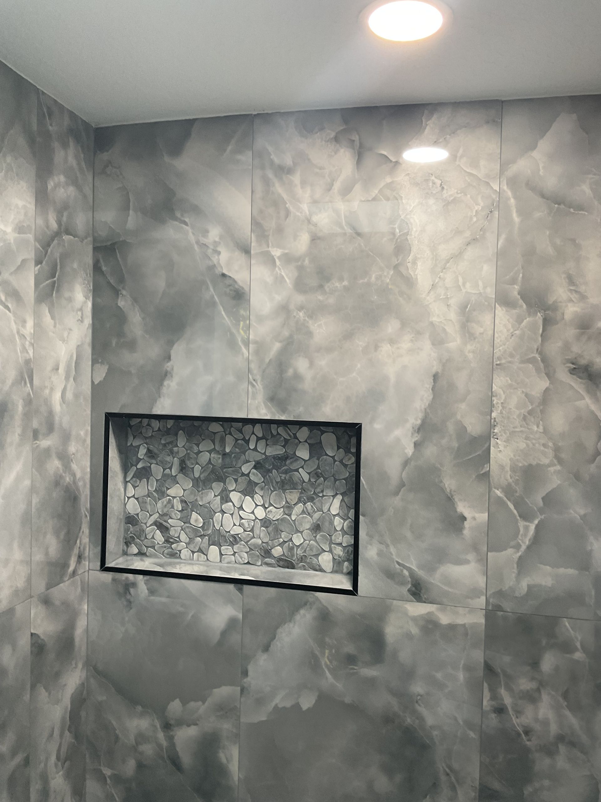 Gray tiled shower wall with a recessed niche and recessed ceiling lights