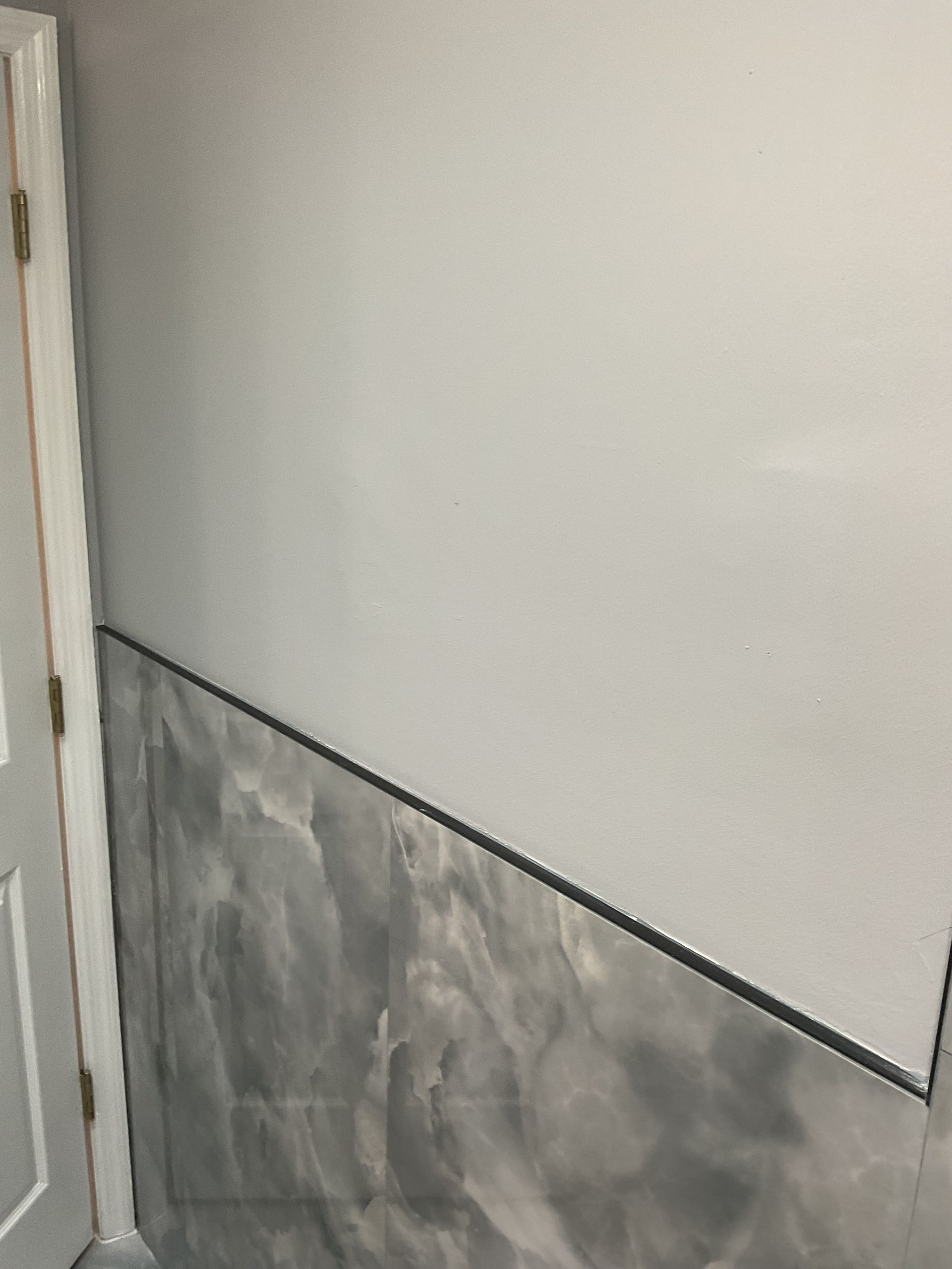 Interior wall with gray water damage or mold staining near a corner and baseboard trim
